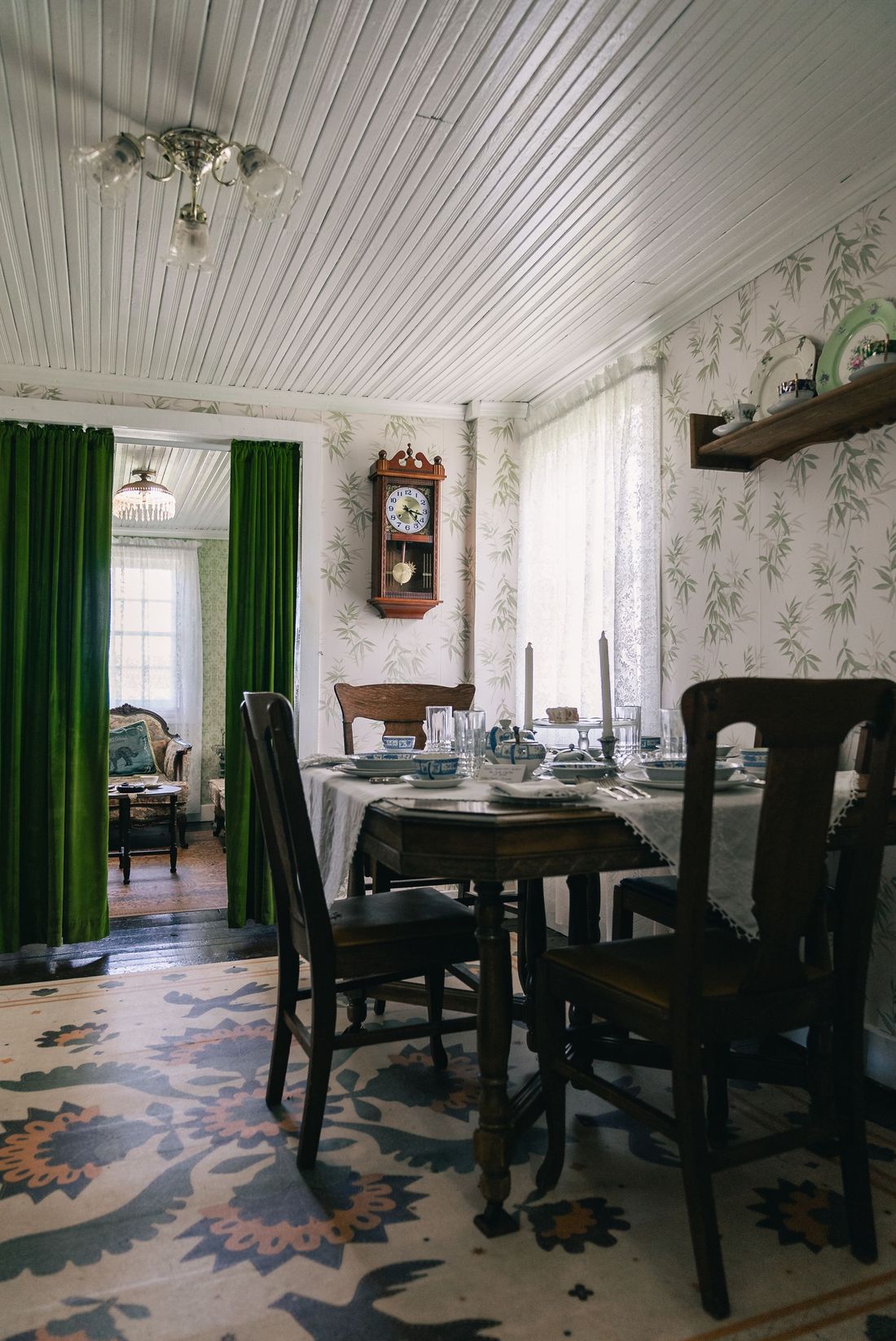 Dining room framed by green drapery with patterned wallpaper