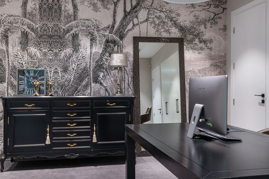 Home study with a forest-scene mural wallpaper behind a dark desk