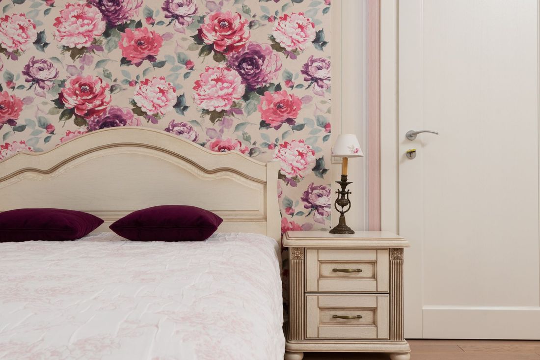 Bedroom accent wall in a pink rose floral wallpaper behind the bed