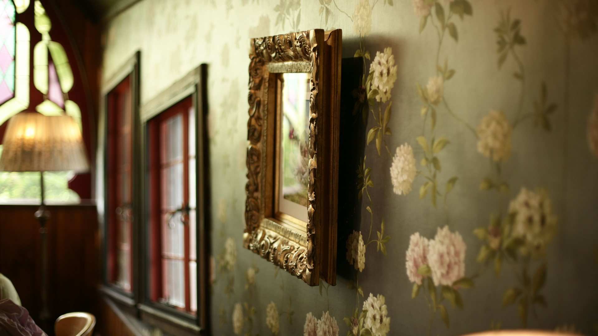 Elegant living room with green floral wallpaper and a gilt-framed mirror