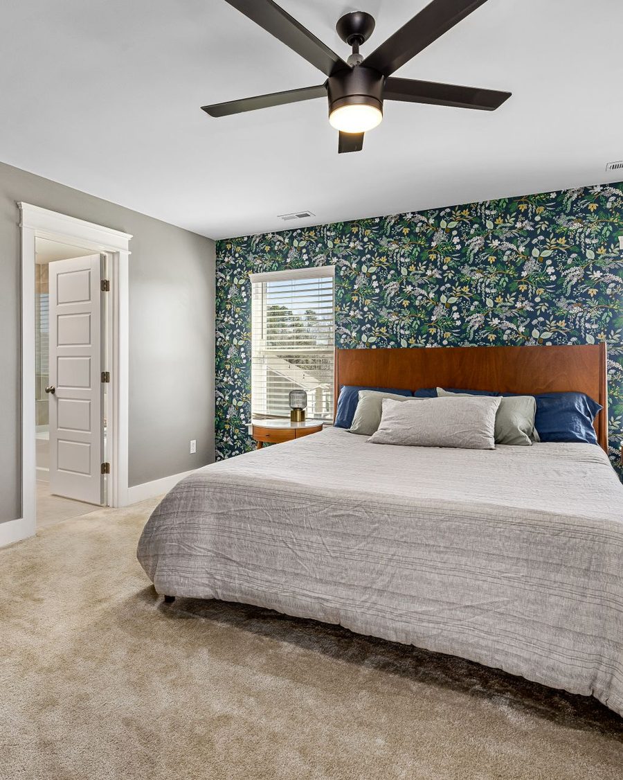 Bedroom feature wall in green botanical wallpaper behind a wooden bed