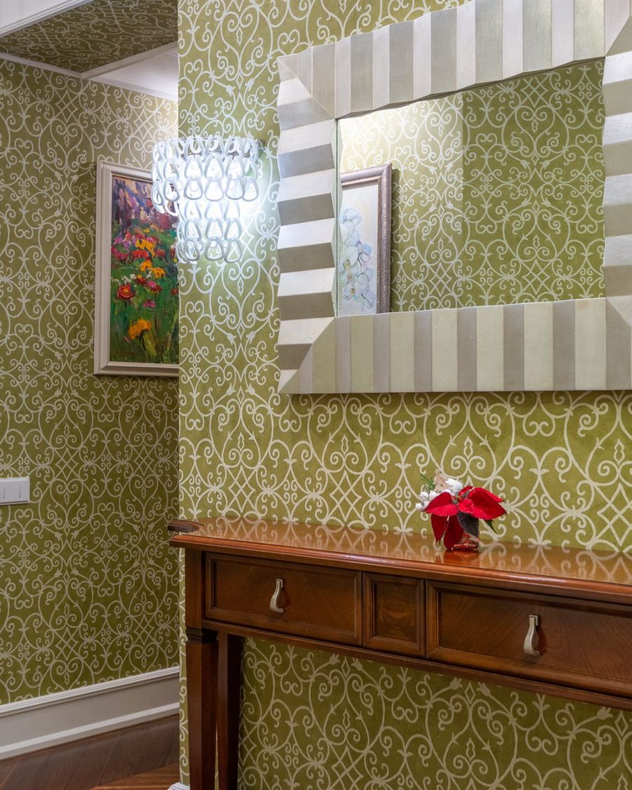 Hallway with green trellis wallpaper above a console table