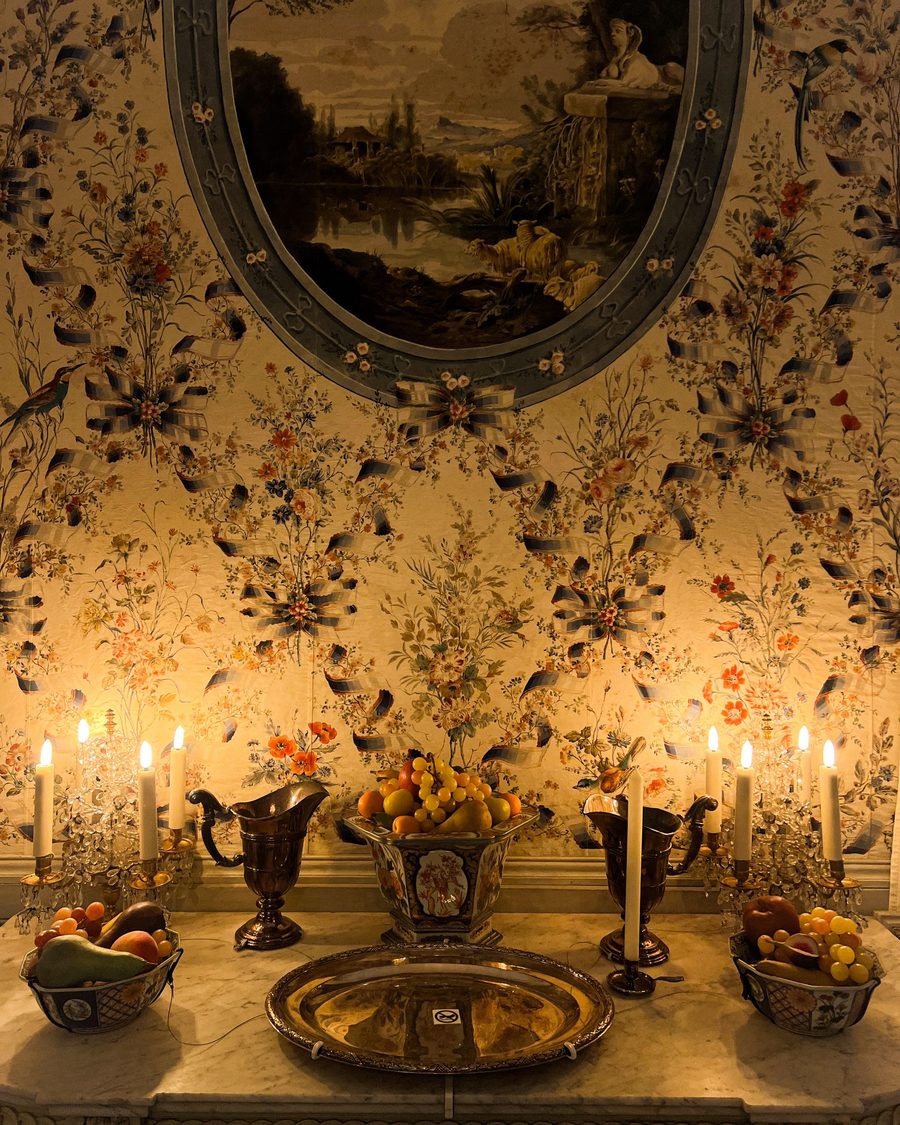 Candlelit vignette against a decorative botanical wallpaper